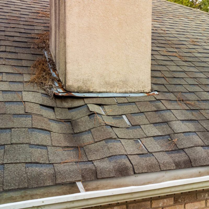 roof with damage, either water or end-of-life damage around the chimney